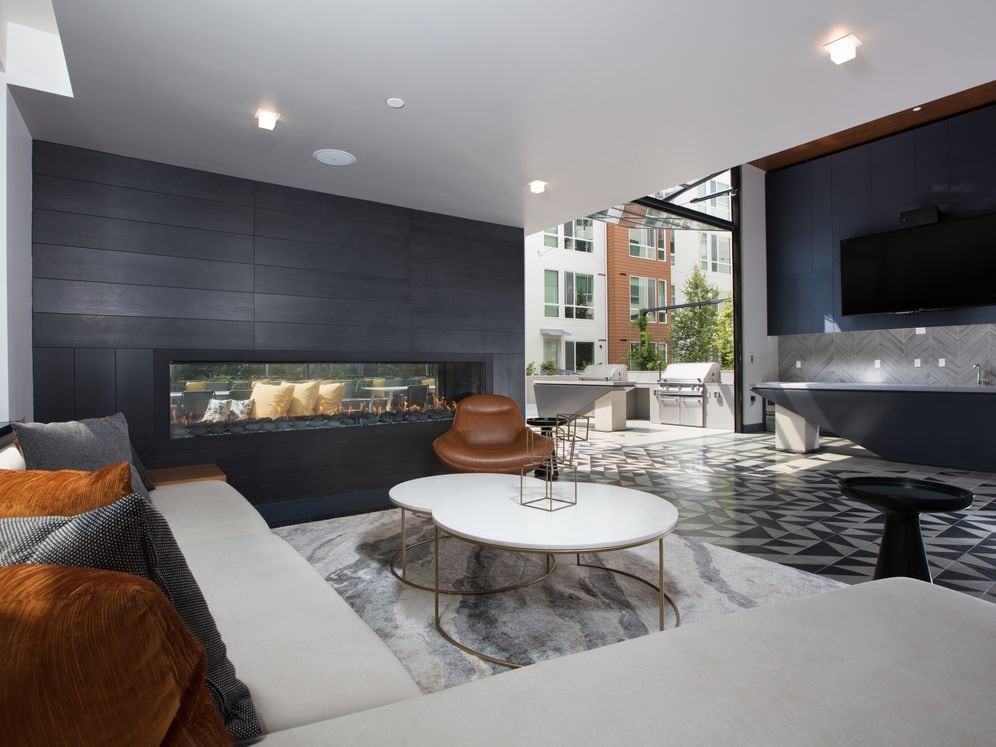 Resident lounge with flat screen television, common area seating, fireplace and patio with barbecue grills