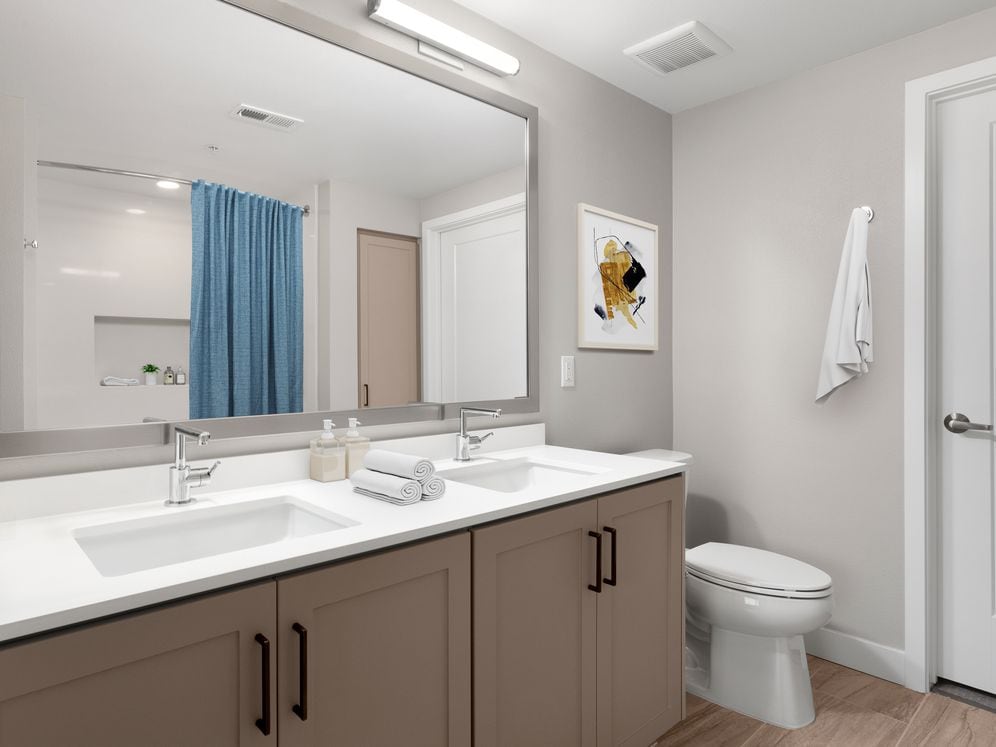 Townhome bath with white quartz countertops, brown cabinetry, and hard surface flooring (select homes)