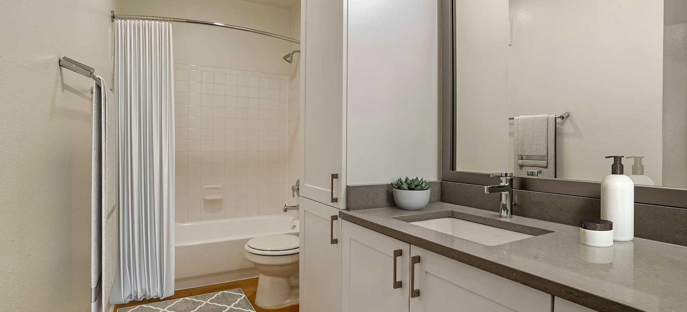 Newly renovated Finish Package V baths with white cabinetry, grey quartz countertops, and hard surface flooring