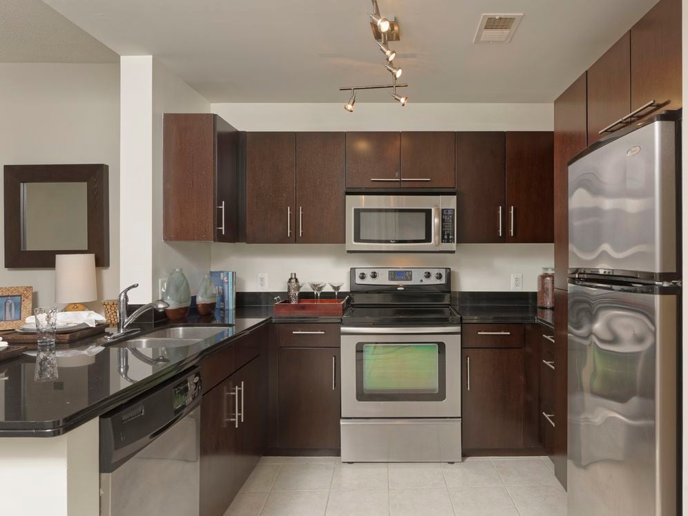 Open concept kitchen with black granite countertops, stainless steel appliances and hard surface flooring