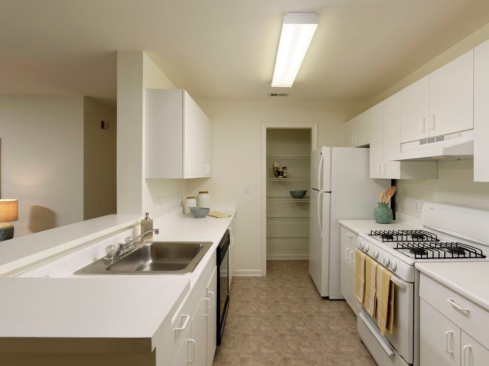 Classic Package I kitchen with white cabinetry, white laminate countertops, white appliances, and vinyl tile flooring