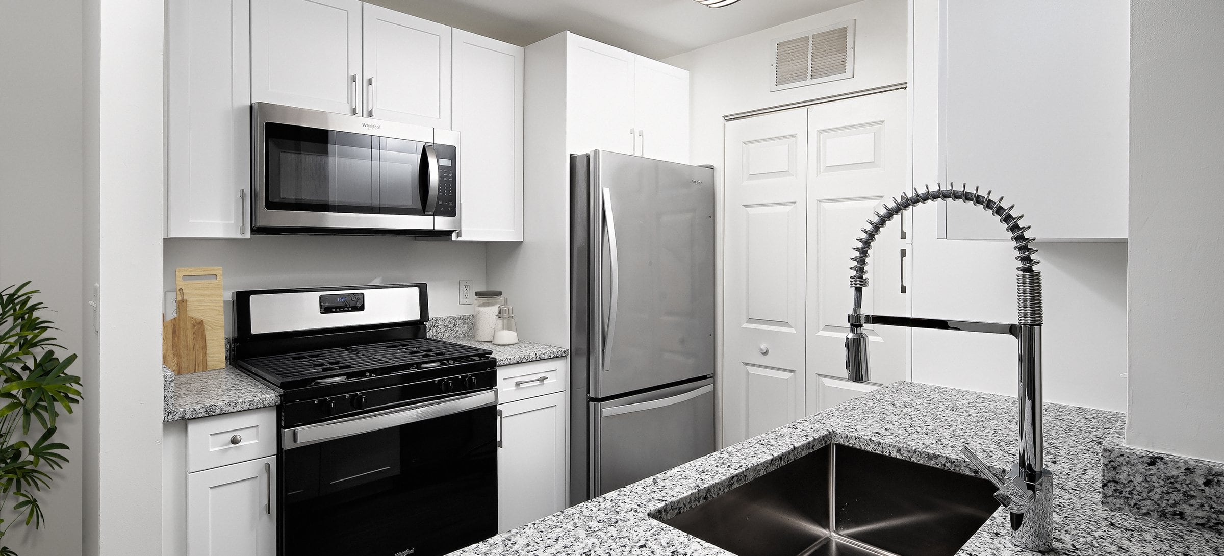 Phase I Renovated apartment kitchen with white cabinetry, quartz countertops, and stainless steel appliances