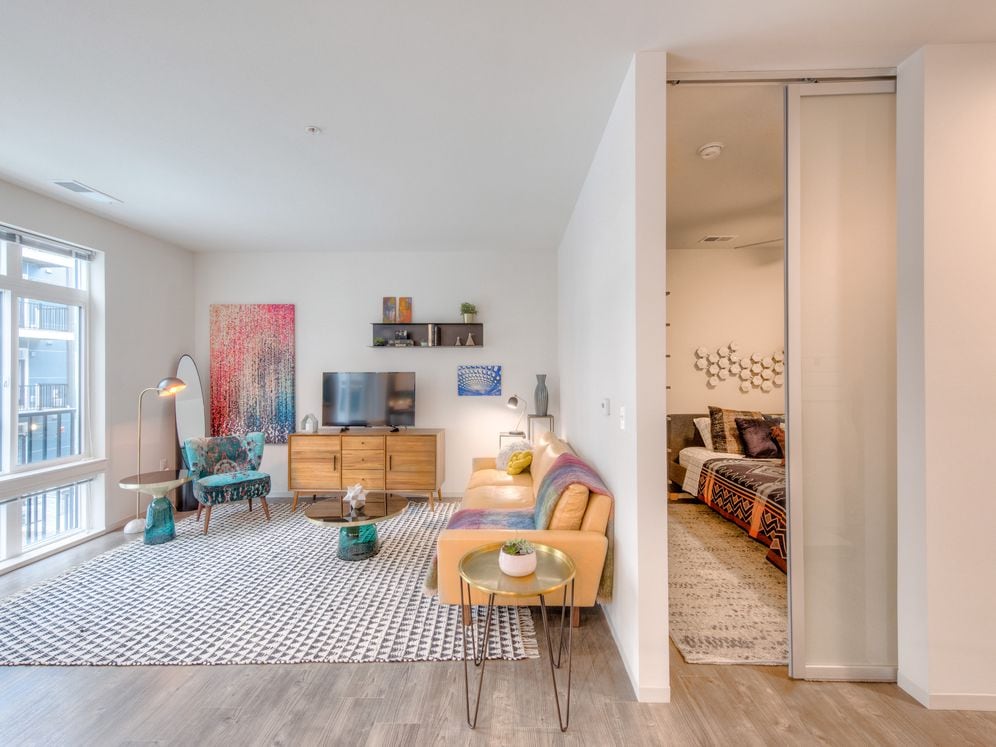 Living area and bedroom with hard surface flooring and sliding barn door