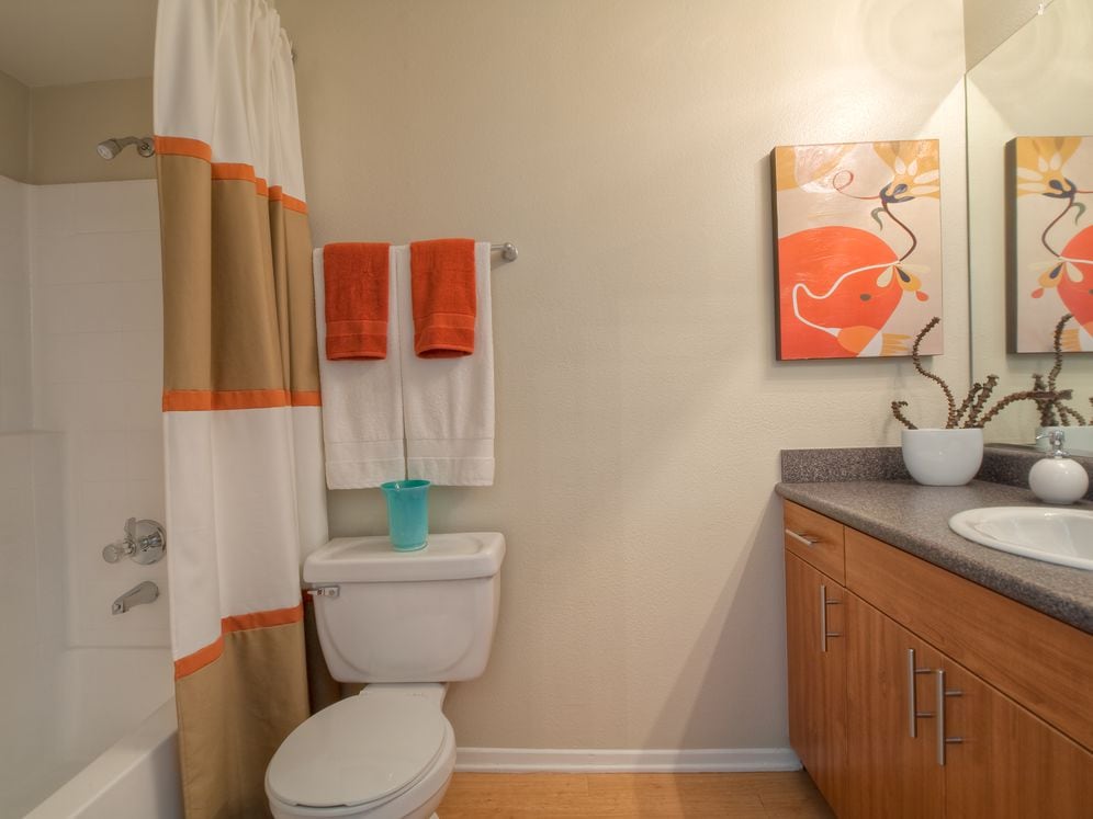 Classic Package bath with grey speckled laminate countertops, oak cabinetry, and hard surface flooring