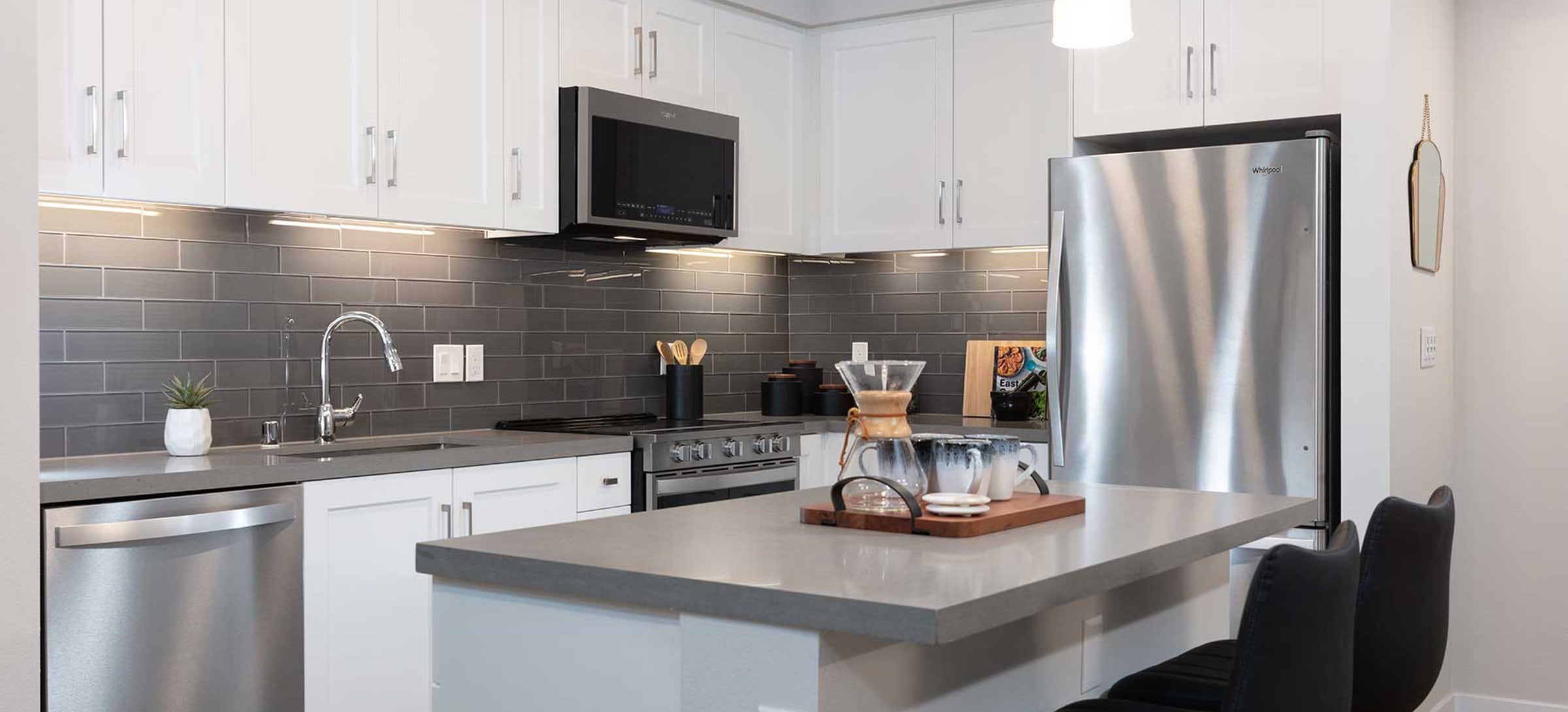 Upgrade Collection kitchen with stainless steel appliances, white cabinetry, grey quartz countertop, grey tile backsplash, and hard surface flooring