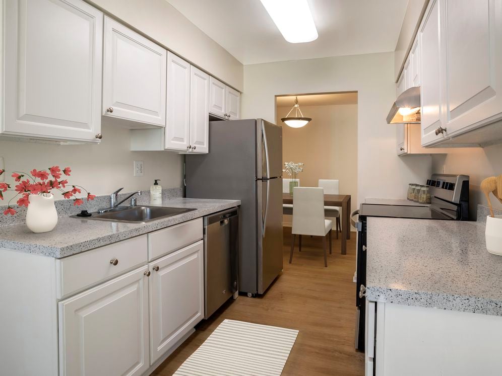 Renovated Package I kitchen featuring stainless steel appliances, white cabinetry, grey laminated countertops, and hard surface flooring