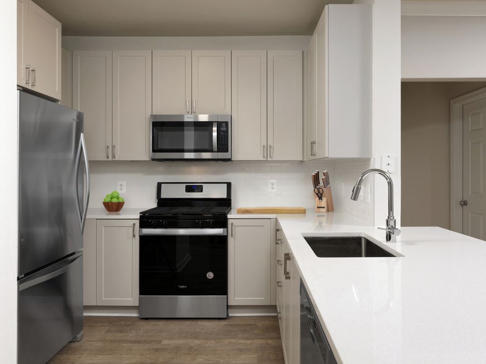 Renovated II kitchen with grey cabinetry, white quartz countertops, stainless steel appliances, white tile backsplash, and hard surface flooring