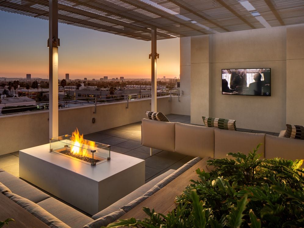 Roofdeck at dusk with outdoor fireplace, flatscreen television, lounge seating and panoramic views