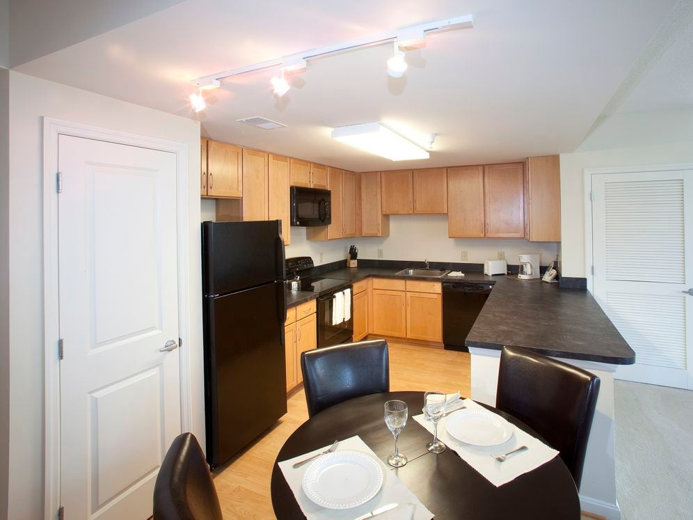 Dining area and kitchen with black appliances, black countertops and hard surface flooring