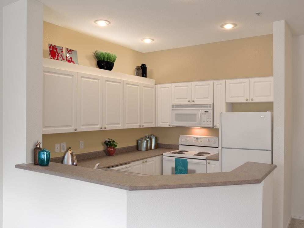 Classic Package I kitchen with white appliances, laminate countertops, white cabinetry, and laminate or hard surface flooring