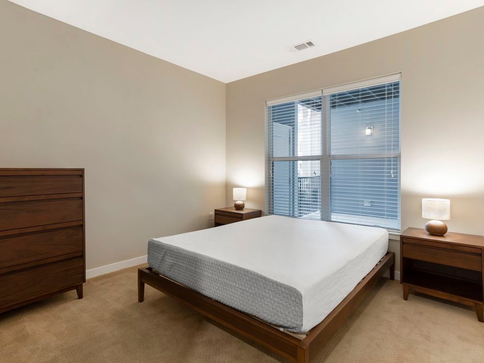 Furnished+ apartment homes feature queen bed with mattress, dresser, nightstands, and lamp (Representative Image – exact items and style of furnishings may vary)