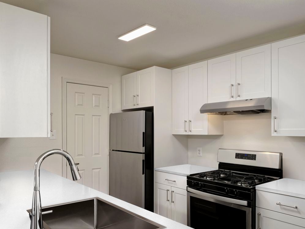 Updated kitchen with white cabinetry, white quartz countertops, stainless steel appliances, and hard surface flooring